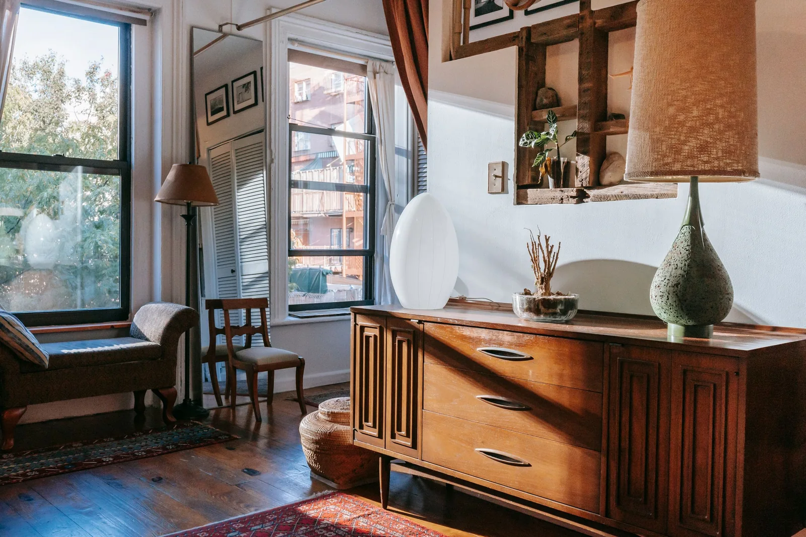 A sunlit living room with low sun pouring through tall windows across a wooden floor