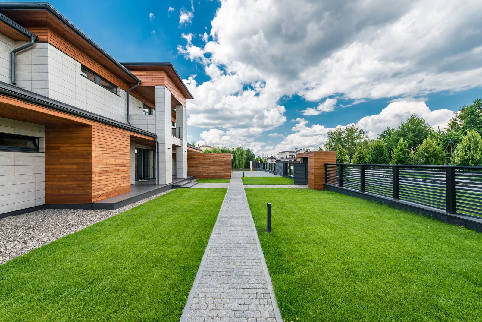 A modern house with tall windows across its front, set back behind a green lawn